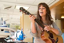 An SPU music therapy alum plays her guitar in a hospital.