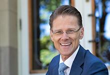 Seattle Pacific University's 10th president Daniel J. Martin sitting on the steps of McKinley Hall.